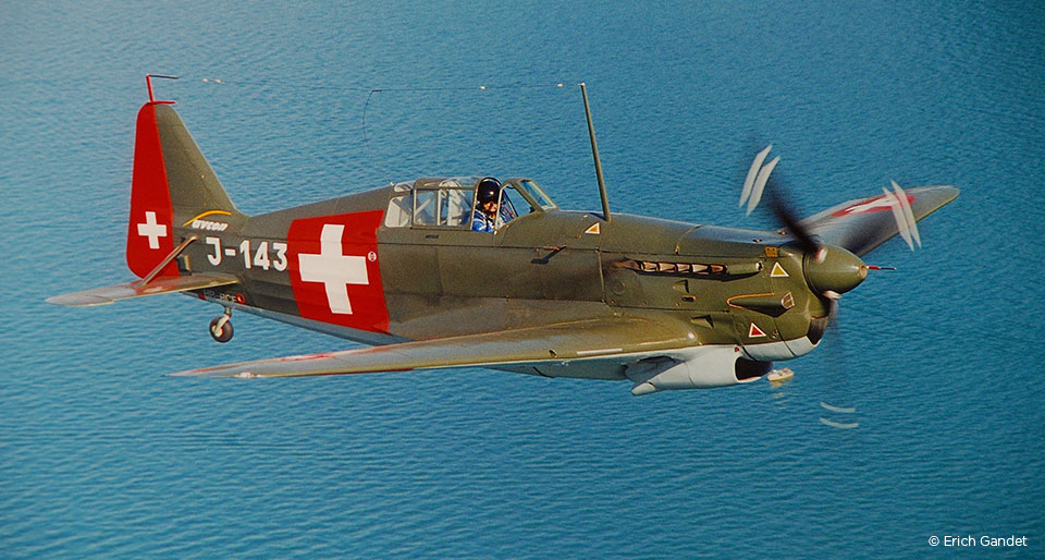 Historisches Schweizer Militärflugzeug im Flug über einem See