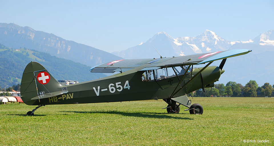 Grünes Militär-Verbindungsflugzeug im Landeanflug vor den Alpen