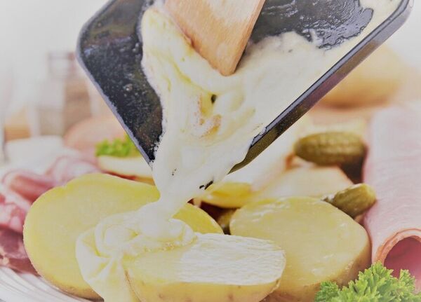 Raclette wird über Kartoffeln geschabt